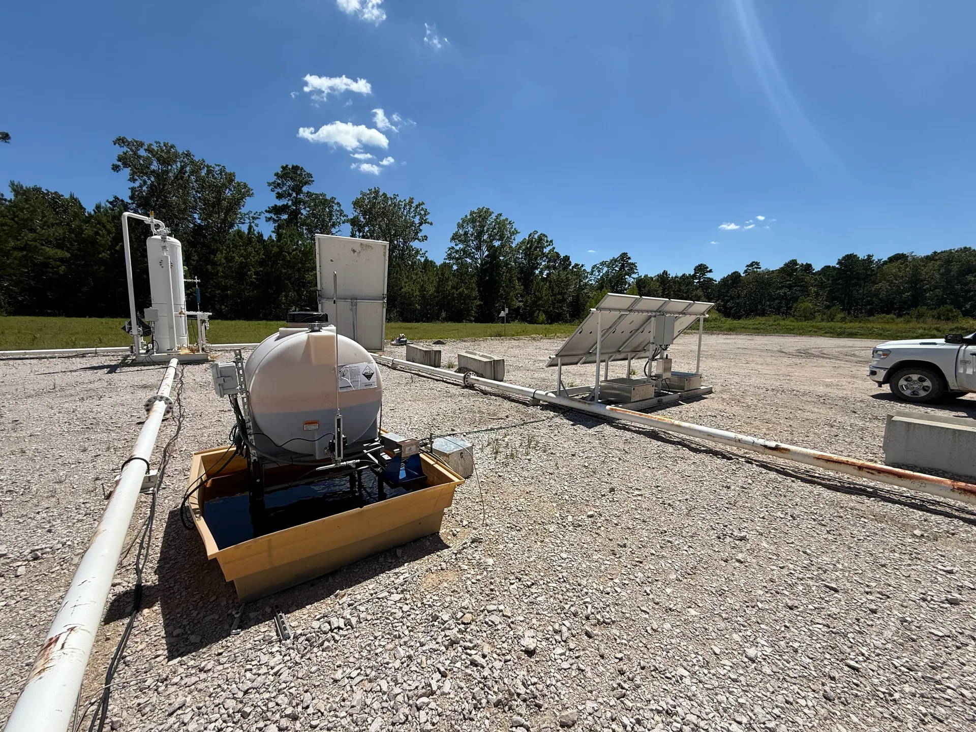 Chemical tank with containment berm and solar array at industrial site