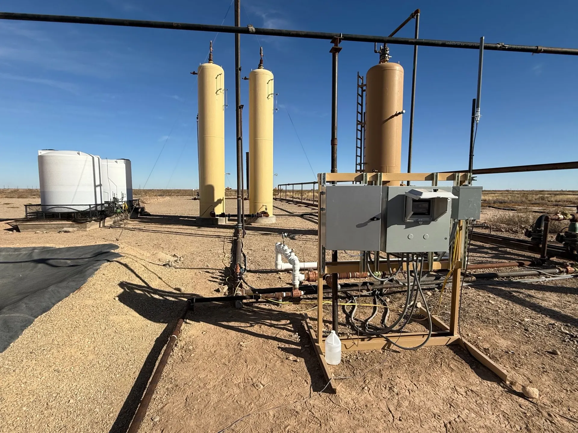 Smart H2S system with electrical panels, tanks, and piping at well site